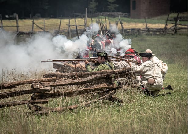 Reenactors firing muskets at the Battle of Huck's defeat